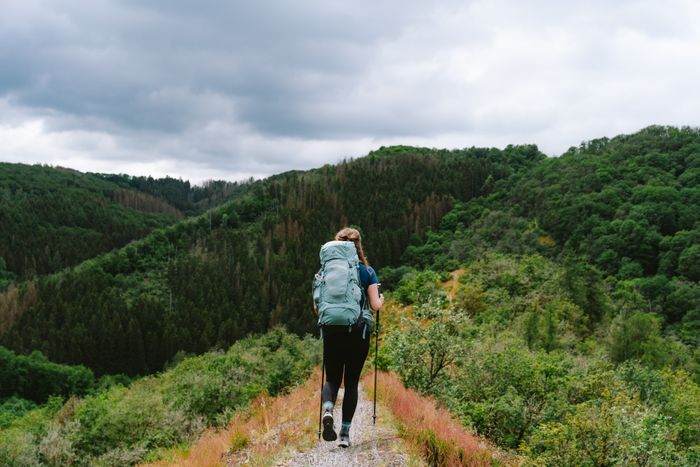 A woman, seen from behind, hikes along a ridge on the Lee Trail with a large green backpack.